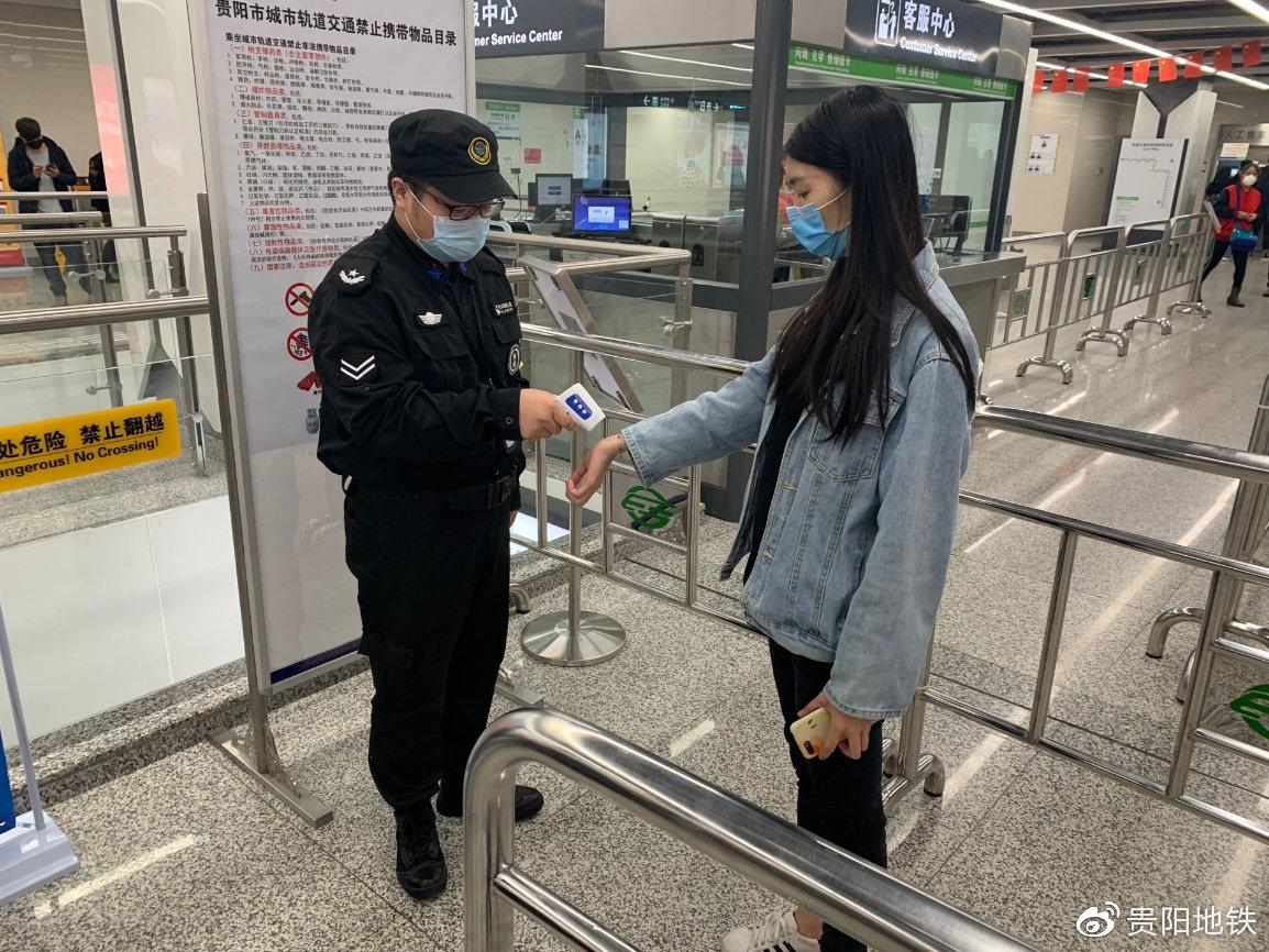 车站工作人员为乘客测量体温