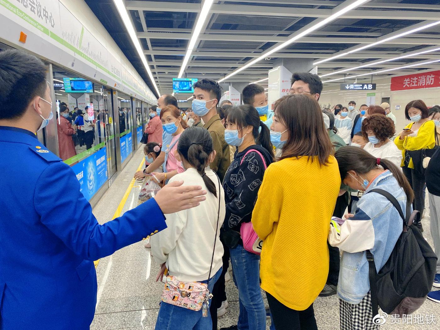 工作人员提醒乘客佩戴好口罩排队候车